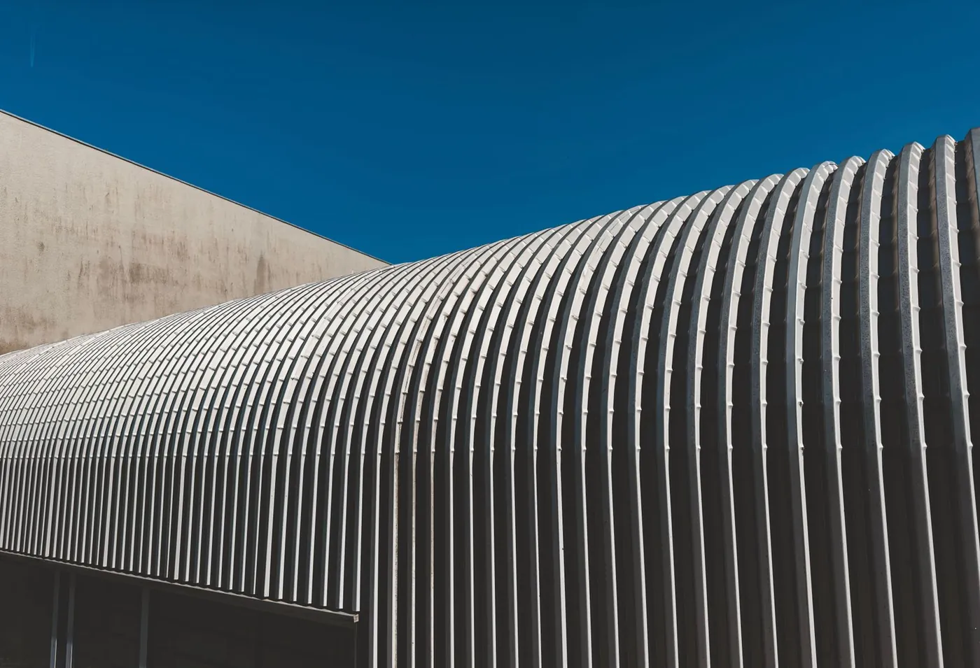 Curved standing seam metal roof on a commercial building against a blue sky