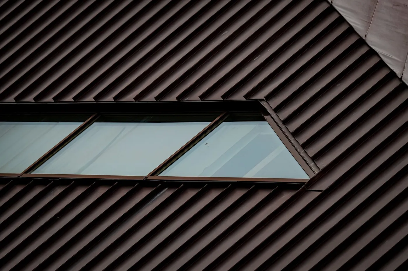 Dark bronze standing seam metal roof with a strip of skylights